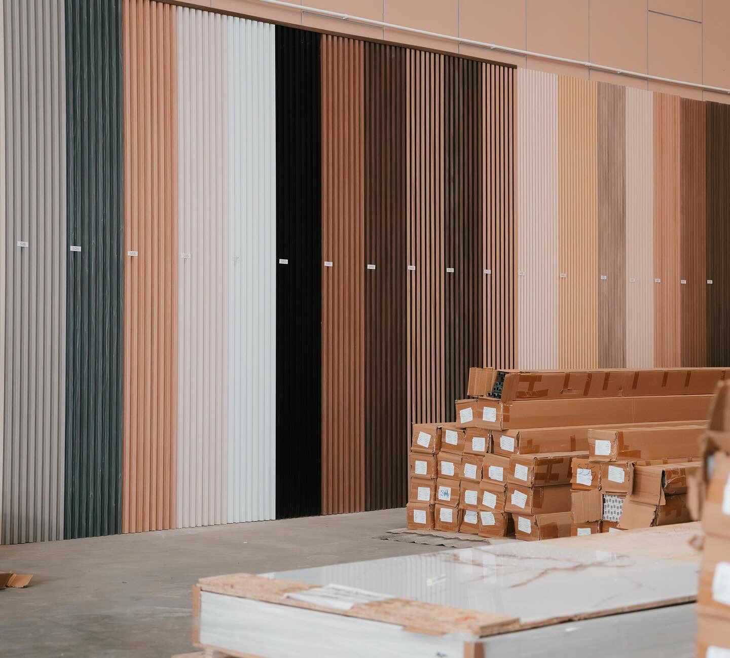 Display wall of decorative vertical slat wall panels in wood tones