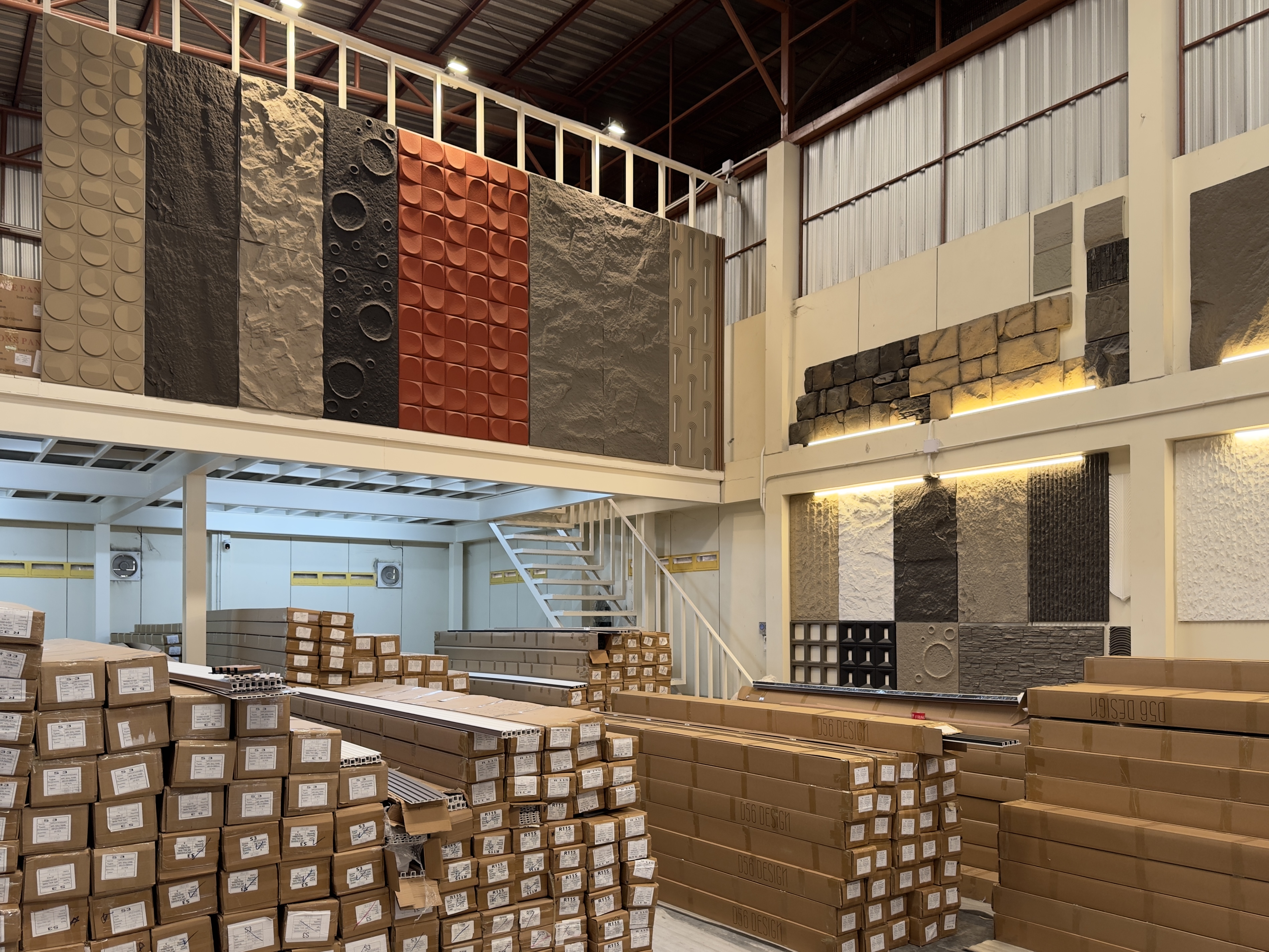 D56 Design warehouse floor stacked with boxed wall panel stock under a display of 3D textured feature panels